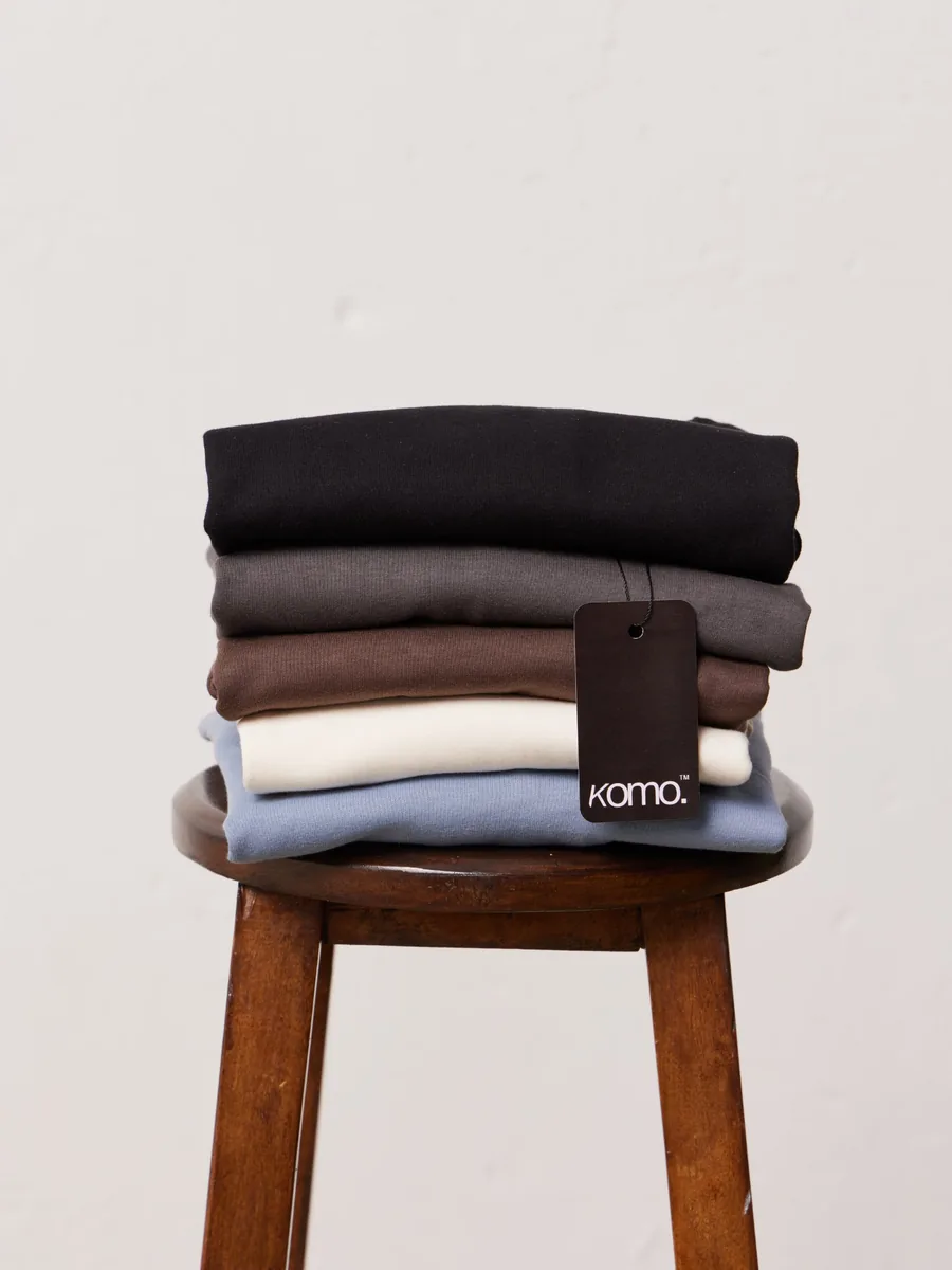 Pilha de camisetas dobradas com etiqueta Komo